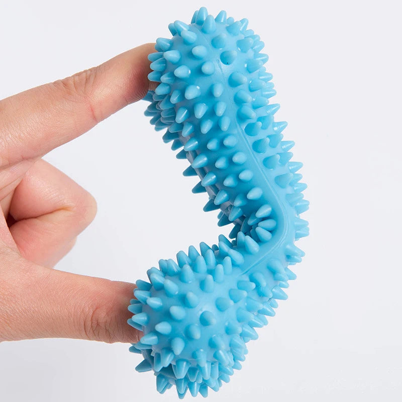 Blue durable dog chew toys with textured spikes held between two fingers by Snugll pets