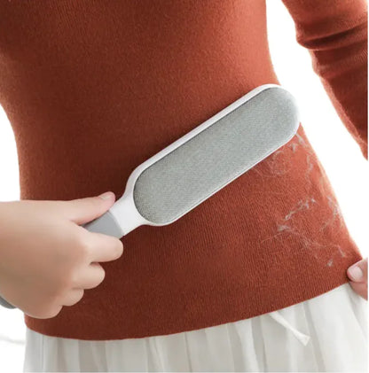 Snugll electrostatic pet hair remover brush cleaning pet hair off a brown sweater
